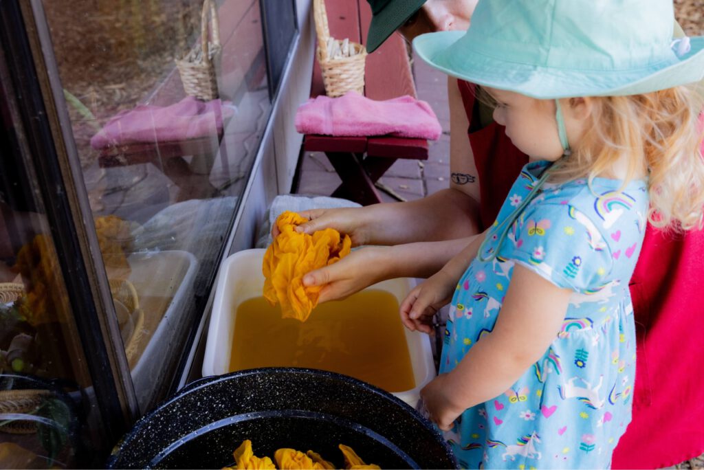 Child engaging in hands-on outdoor activity with teacher at Madison Waldorf School